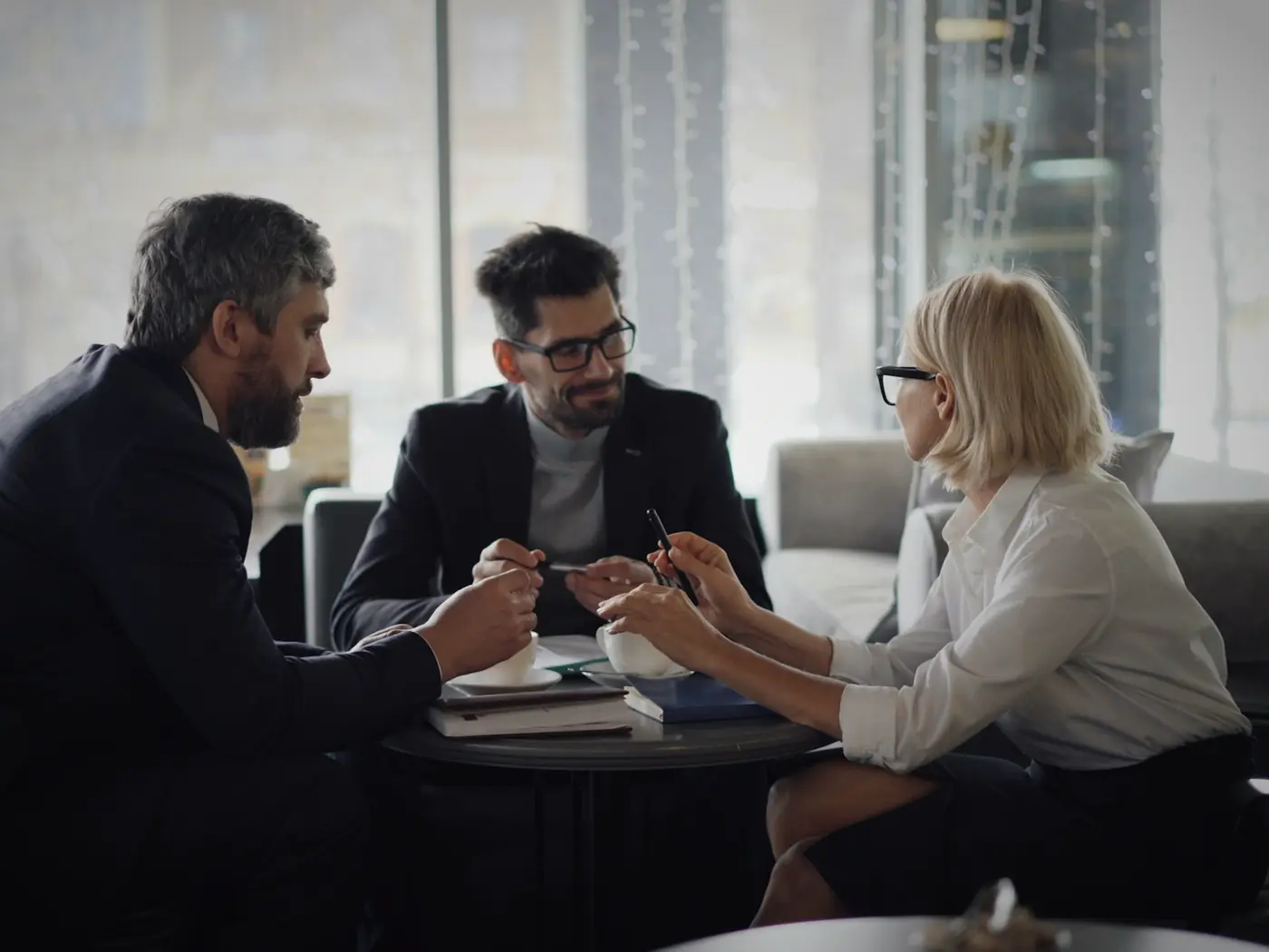 Consultores conversando com uma cliente em uma mesa de reunião